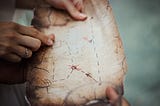 two people examine an old map made of parchment