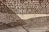 wood latices hanging from the ceiling of a beige foyer.