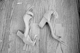 A pair of heels lie on a hardwood floor