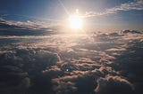 A picture of clouds and the evening sun, from the perspective of an airplane window.