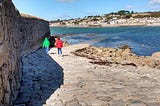 It shows two children on a cobbled road that disappears into the sea. It shows how a road can be difficult to follow.