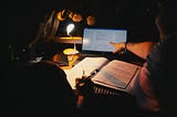A student studies late at night, surrounded by notes and a laptop, illustrating academic pressure and exhaustion