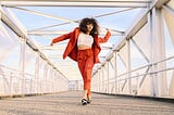 A Black woman in a red suit dancing across a bridge. trump, news, Black peopel