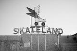 A black and white photo of a vintage sign for Skateland in Memphis, Tennessee including a large roller skate with wings.