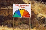 A sign reading “fire danger today — low, moderate, high, very high, extreme” with an arrow pointing to extreme.