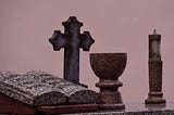 A photo of a gravestone formed to look like an open book with a cross and goblet.