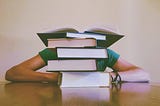 Person hidden behind stack of books