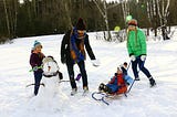 Family playing in the snow building snowman and snowballs