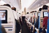 The aisle of an aircraft showing the backs of the row of aisle seats