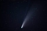 A comet with two tails is passing in the night sky