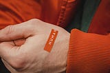 a close up of a human hand with a label “human” on the hand. the background is the person’s torso who is wearing a button down jacket