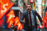 A businessman in a suit urgently rushes through a busy street filled with glowing neon signs.