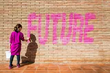 Young girl painting the word “Future” on a brick wall