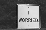 ‘I Worried’ the word is written on a white board in front of a dark background.