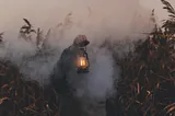 An arm holding a kerosene lantern. There’s a person hidden in the smoke, and it’s not quite clear where they should be going.
