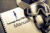 The image shows a spiral-bound manual titled “Teenage Boy (TB) Manual,” featuring an illustrated boy wearing a hoodie, pants, and sneakers on the cover. Surrounding the manual are protective gear items, including safety goggles and earmuffs, placed on a dark surface.