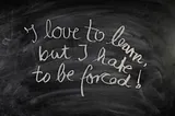 Image by Gerd Altmann from Pixabay. Image Description: The sentence “I love to learn but I hate to be forced!” is written in chalk on a blackboard.