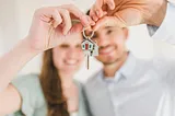 A man and a woman both holding the keys to a new house.