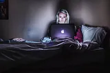 A woman in bed working on her computer