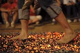 Photo of person walking barefoot on glowing burning coals