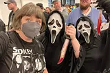 A woman poses with two people in Scream costumes at ECCC