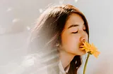Young woman smells flowers with eyes closed, enraptured