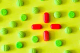 An array of green and red pills against a yellow background.