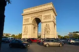 A large arch is surrounded by cars traveling around it