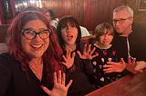 A family of four making jazz hands at a dinner table.