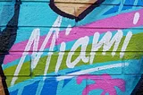 A picture of a t-shirt with only a little neckline showing. The point is to accentuate that it reads Miami and is part of what appears to be street art.