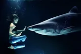 A girl meditating under water in front of a shark