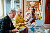 Three people sitting at a table looking at papers.