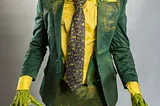 A green lizard-likemonster in a green business suit and yellow shirt