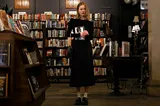 A woman standing in a bookstore holding a book