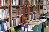 Book shelves full of books and a table with more books