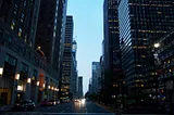 A street in New York. Tall sky scrapers on both sides.