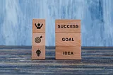 A photo of a stack of blocks labeled from bottom to top with Idea, Goal, and Success.