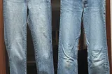 Two pairs of faded blue jeans hang from a door frame