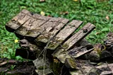 A section of a broken wooden fence lying on the green grass on the ground.