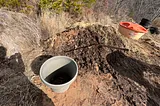 A pile of horse manure with a pitchfork and bucket.