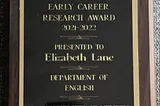 An image of a wooden plaque with a metal plate, engraved with the words Early Career Research Award