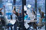 group of business professionals at work in a conference room throwing documents in the air