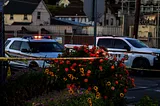 A rose bush is wrapped in crime scene tape at the scene of a law enforcement shooting at dusk. Two Solano County Sheriff’s Office vehicles can be seen in the background.