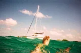 POV flaoting in green sea looking at a yacht