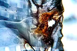 An abstract, unclear blueish photo with part of the image with a small burnt or melted hole, which disfigures the image.