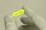 a gray scale image with a yellow pill that says Just relax