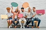 people sitting on bench holding speach bubbles