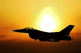 Airplane jet fighter silhouette flying in orange and yellow sunrise