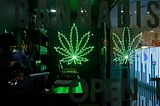 A dark and moody cannabis dispensary with a neon marijuana leaf sign.