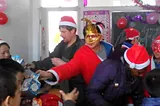 Evan wearing a Santa hat and passing out presents to students.